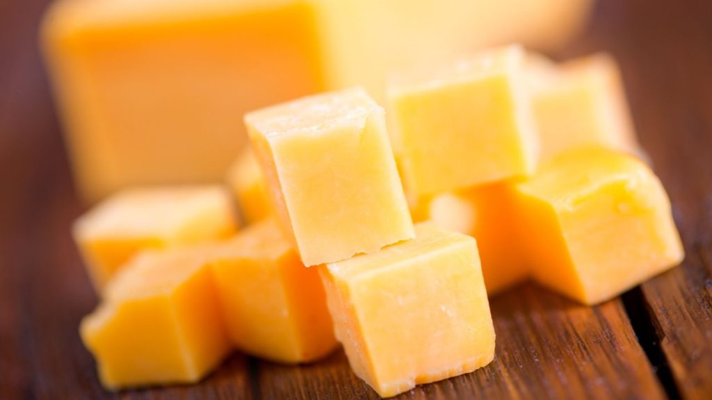 Cubes of cheddar cheese on a table. 