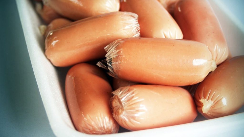 A pack of mini hotdogs on a plate. 