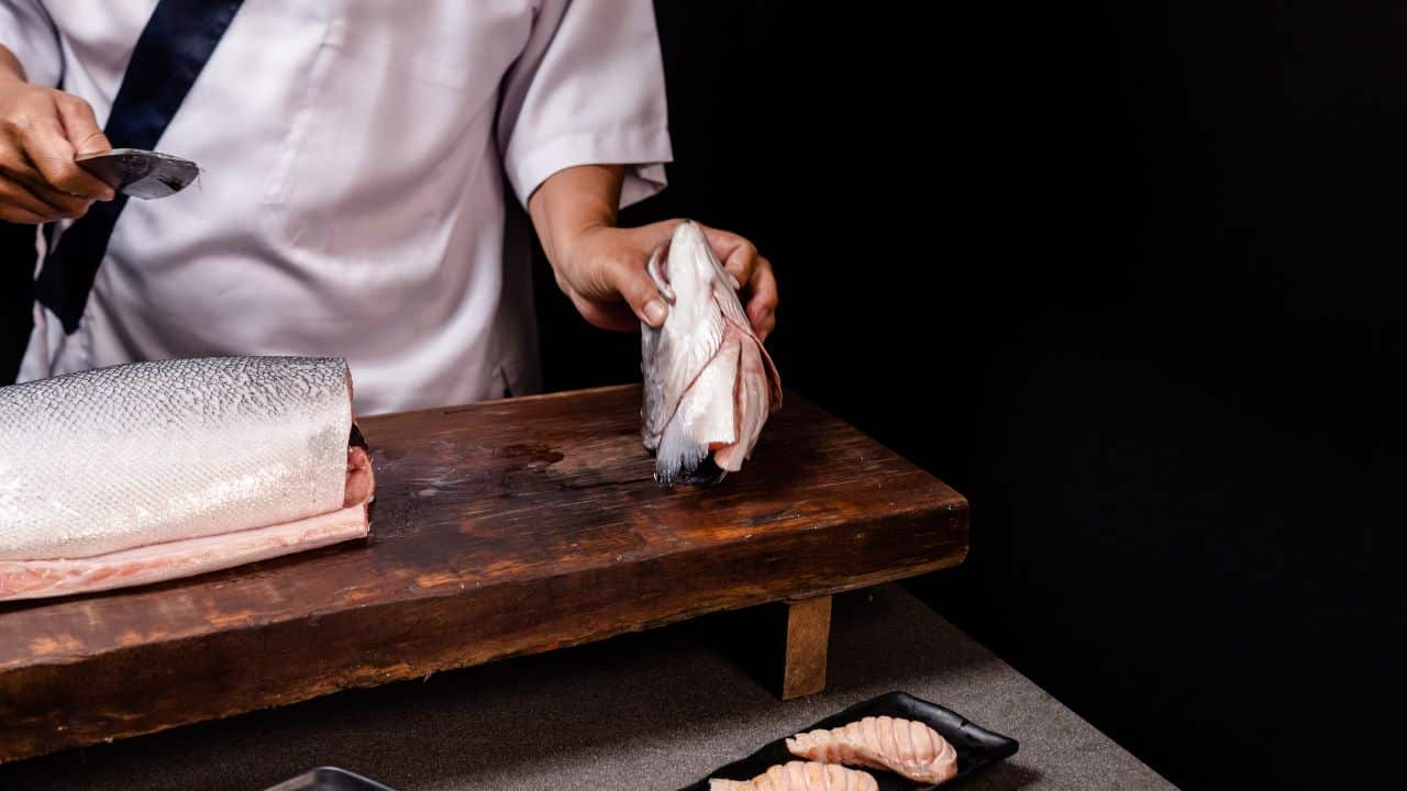 A person deboning or filleting a salmon fish.